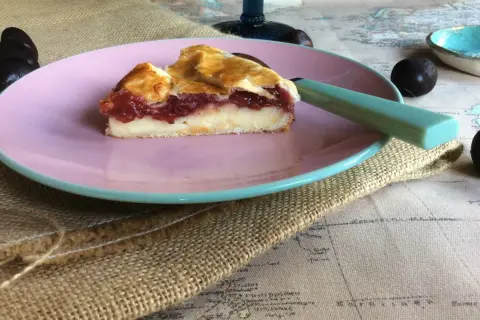 Rebanada de pastel vasco con relleno de crema y mermelada de frutos rojos, servida en plato rosa.
