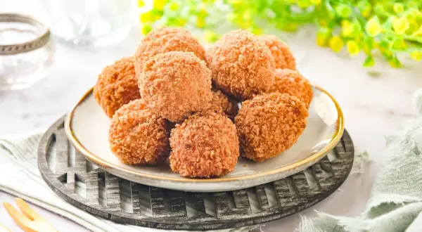 Croquetas de salmón doradas y crujientes, apiladas en un plato, listas para disfrutar.