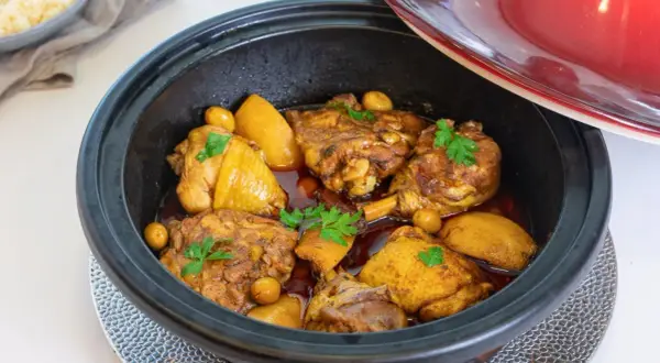 Tajín de pollo con patatas y aceitunas, decorado con perejil fresco. Un plato aromático listo para servir.
