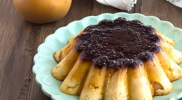 Delicioso pudin de manzana con cobertura oscura, servido en plato turquesa.