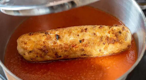 Rollo de bonito dorado y crujiente nadando en una salsa de tomate casera, listo para ser servido.