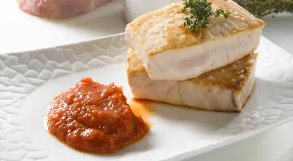 Dos jugosos medallones de atún a la plancha, con sal marina y romero, acompañados de una salsa de tomate casera.