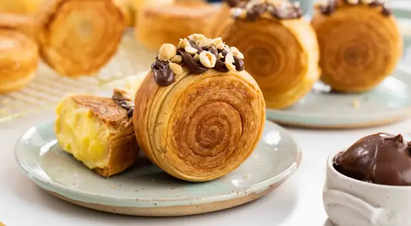 Deliciosos new york rolls cubiertos de chocolate y avellanas, uno abierto revela un cremoso relleno.