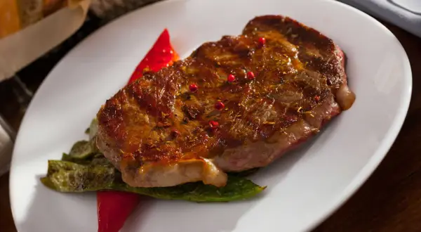 Jugoso entrecot a la plancha, servido con pimientos verdes y un toque de pimientos rojos.