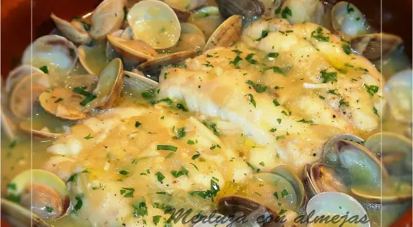 Merluza en salsa verde con almejas, un plato casero de Loli Domínguez, con perejil picado y una salsa cremosa.