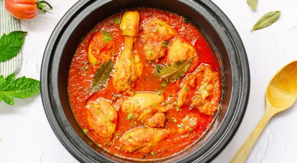 Sabroso pollo con tomate cocinado a fuego lento, con hojas de laurel y perejil picado.
