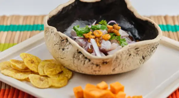 Delicioso ceviche de corvina fresco, servido en un cuenco rústico con patacones y cubos de camote.