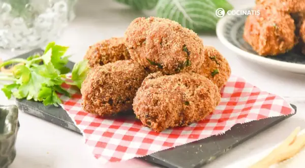 Deliciosas croquetas de atún doradas y crujientes, servidas sobre un mantel de cuadros rojos y blancos.
