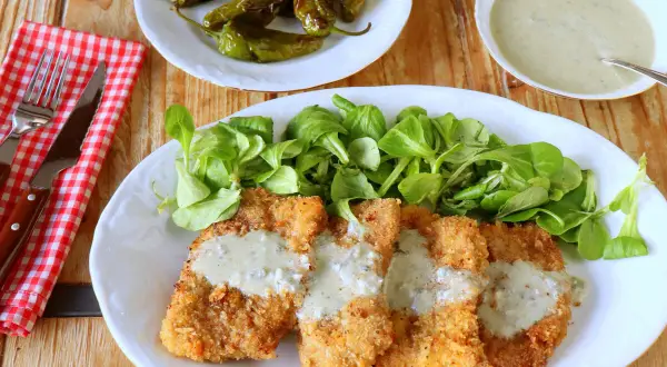 Escalopines al cabrales crujientes, servidos con ensalada verde y pimientos asados. ¡Un plato delicioso!