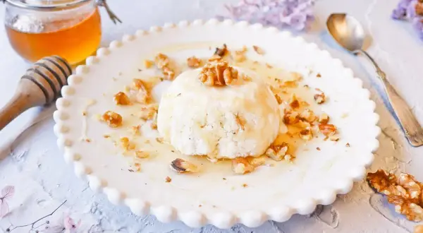 Delicioso mel y mató con nueces, servido en un plato blanco con borde festoneado.