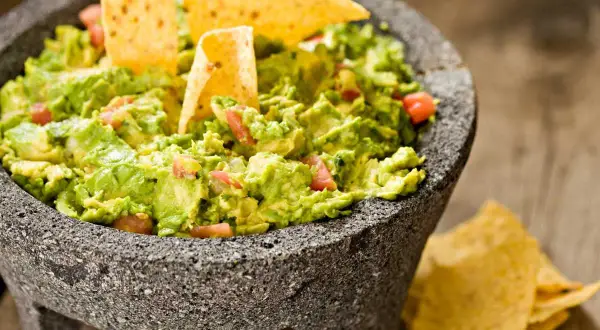 Guacamole fresco en molcajete, listo para disfrutar. Una deliciosa guacamole receta con totopos.
