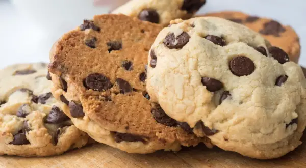 Galletas con pepitas de chocolate recién horneadas, apiladas sobre una tabla de madera.