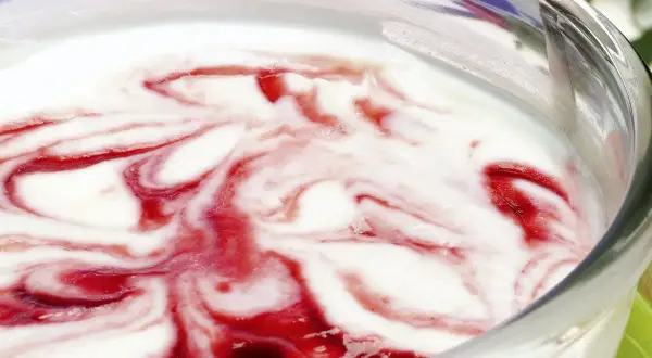 Delicioso helado de queso con remolinos de fresa en un tazón de vidrio.