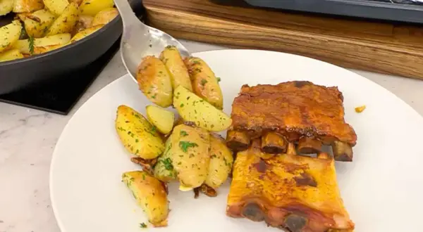 Costillas de churrasco al horno con patatas asadas y hierbas.