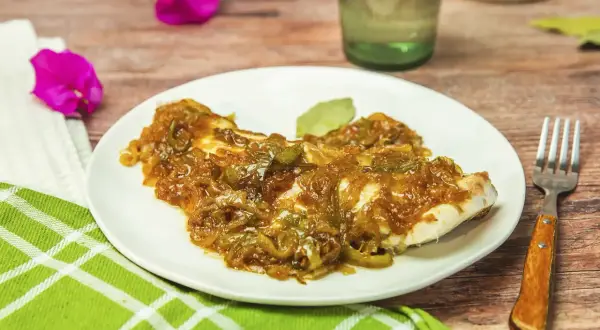 Delicioso plato de urta a la roteña, con pescado blanco cubierto de cebolla caramelizada y pimientos verdes.
