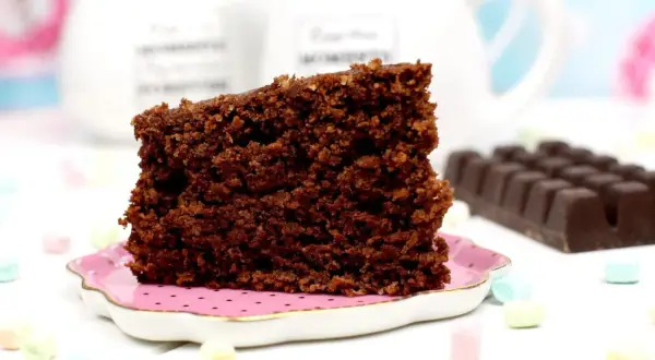 Un trozo de bizcocho de avena de chocolate, esponjoso y delicioso, servido en un plato rosa.
