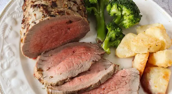 Jugoso roast beef cortado en rodajas, acompañado de brócoli al vapor y patatas asadas crujientes. Un festín para los sentidos.