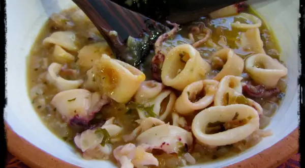 Calamares en salsa, un plato casero con trozos tiernos y tentáculos, servido en un cuenco de barro.