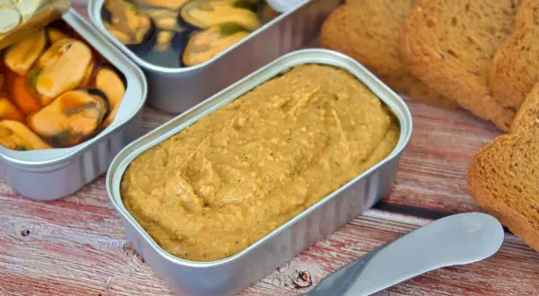 Un paté de mejillones cremoso en lata, junto a mejillones en conserva y tostadas.