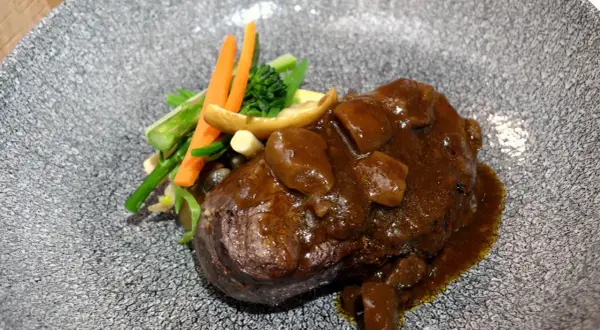 Delicioso solomillo en salsa de la abuela, acompañado de verduras frescas y champiñones. Un plato que evoca recuerdos y sabores caseros.