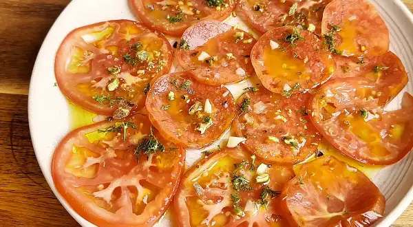 Delicioso carpaccio de tomate con aceite de oliva, ajo picado, hierbas frescas y trocitos de pistacho.
