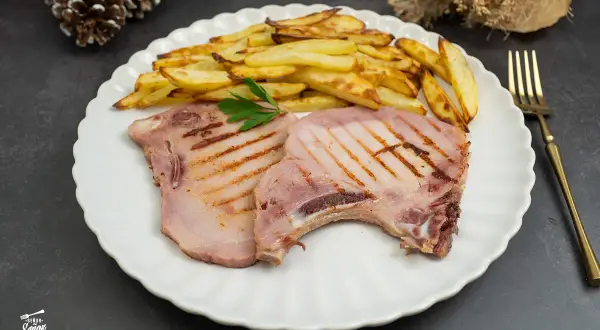 Dos chuletas de sajonia a la parrilla con patatas fritas y perejil. Un plato delicioso y listo para disfrutar.