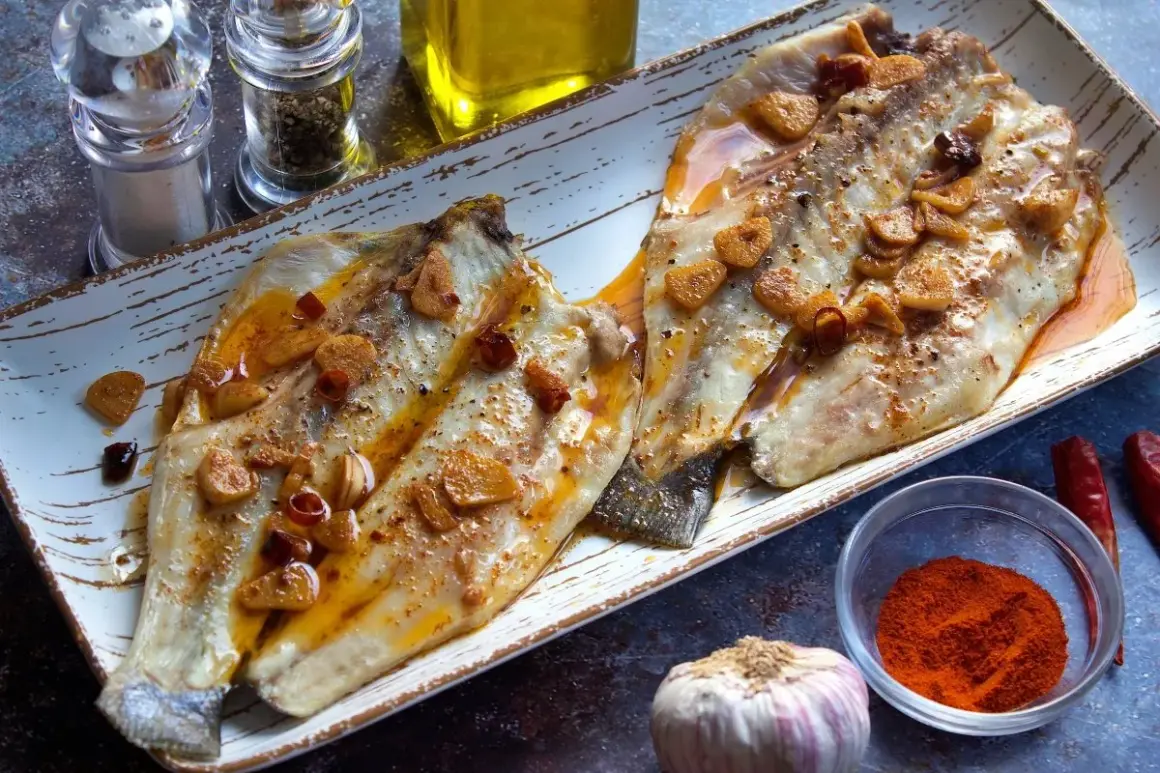 Dos filetes de lubina a la bilbaina, dorados y jugosos, con láminas de ajo crujiente y guindilla.