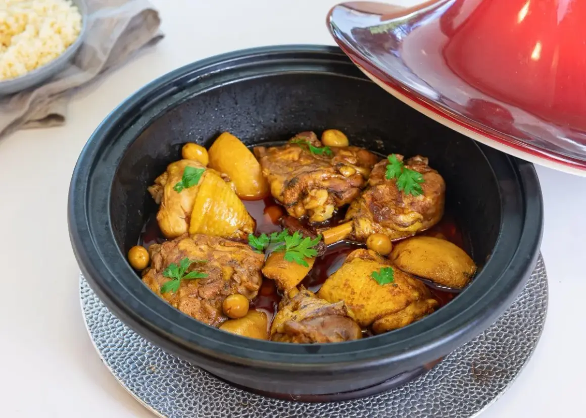 Tajín de pollo con patatas y aceitunas, decorado con perejil fresco. Un plato aromático listo para servir.