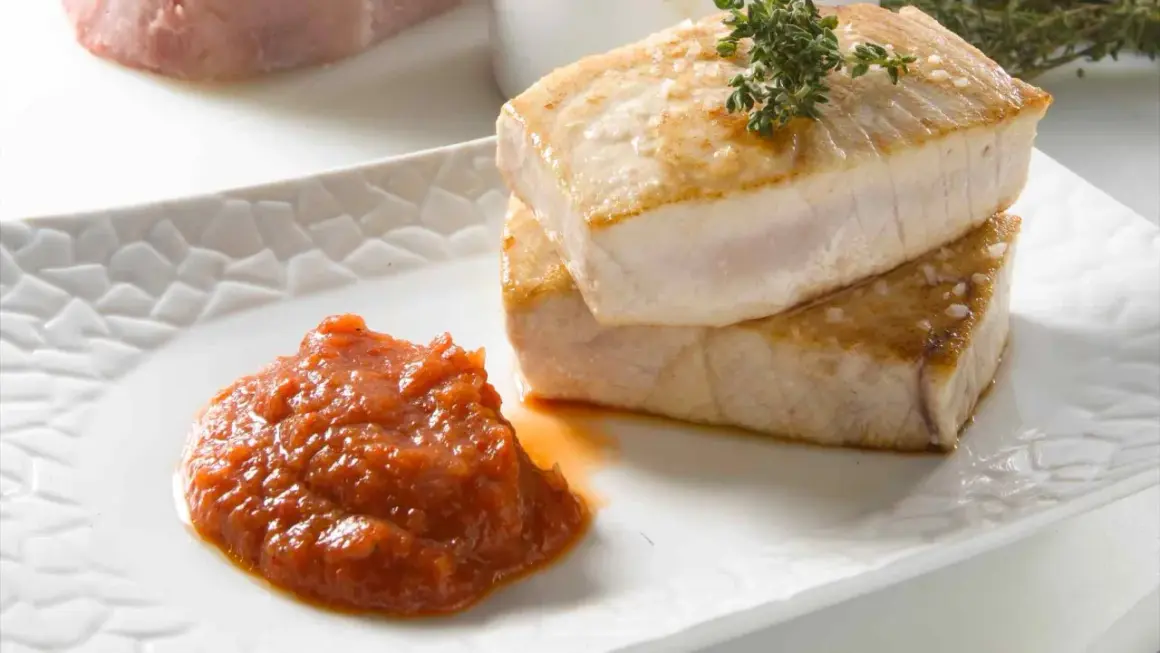 Dos jugosos medallones de atún a la plancha, con sal marina y romero, acompañados de una salsa de tomate casera.