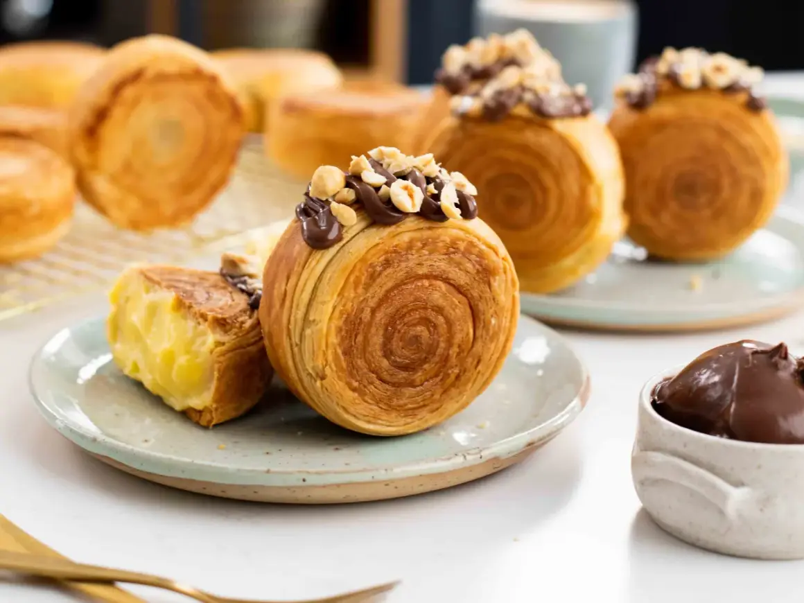Deliciosos new york rolls cubiertos de chocolate y avellanas, uno abierto revela un cremoso relleno.