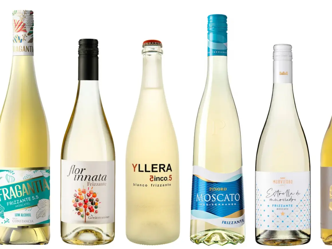 Seis botellas de vino blanco, algunas con etiquetas que indican que son frizzante, como Fragantia y Yllera Cinco.5.