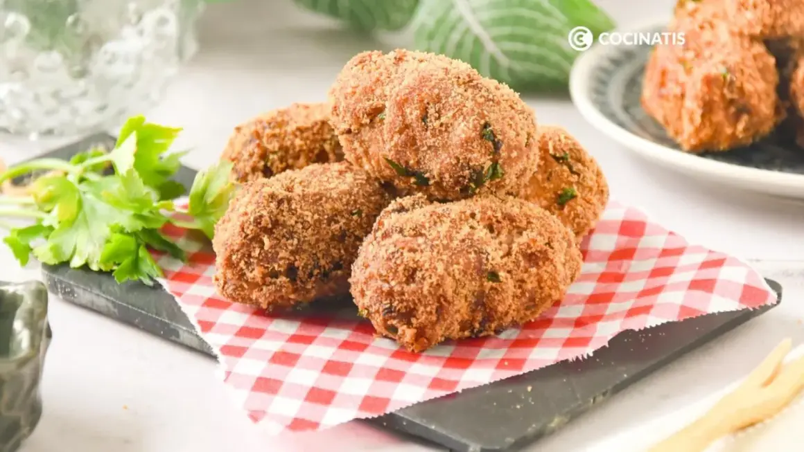 Deliciosas croquetas de atún doradas y crujientes, servidas sobre un mantel de cuadros rojos y blancos.