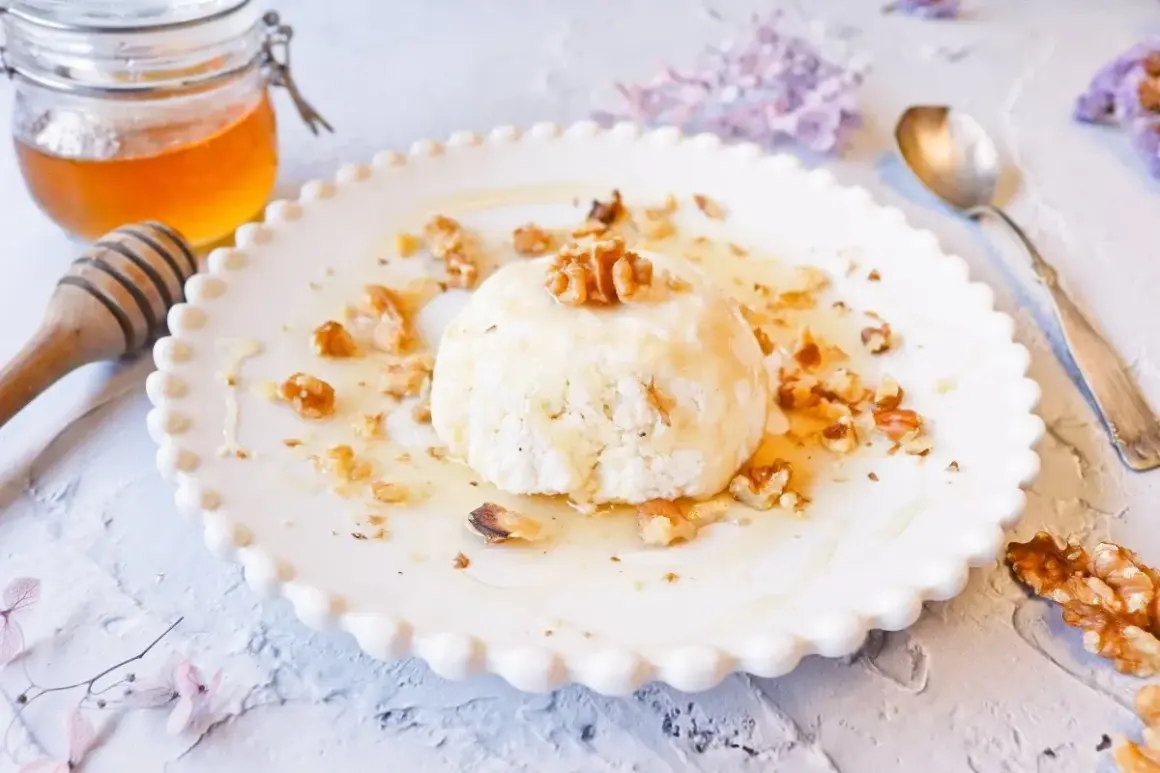 Delicioso mel y mató con nueces, servido en un plato blanco con borde festoneado.