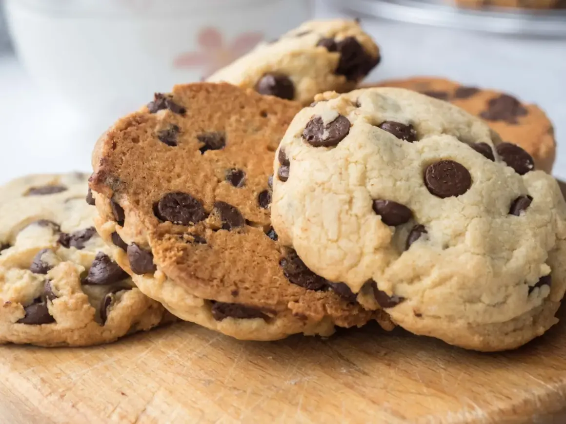Galletas con pepitas de chocolate recién horneadas, apiladas sobre una tabla de madera.