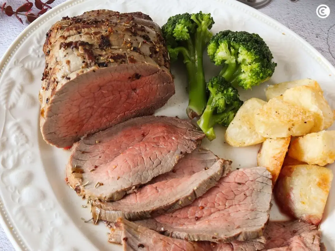 Jugoso roast beef cortado en rodajas, acompañado de brócoli al vapor y patatas asadas crujientes. Un festín para los sentidos.