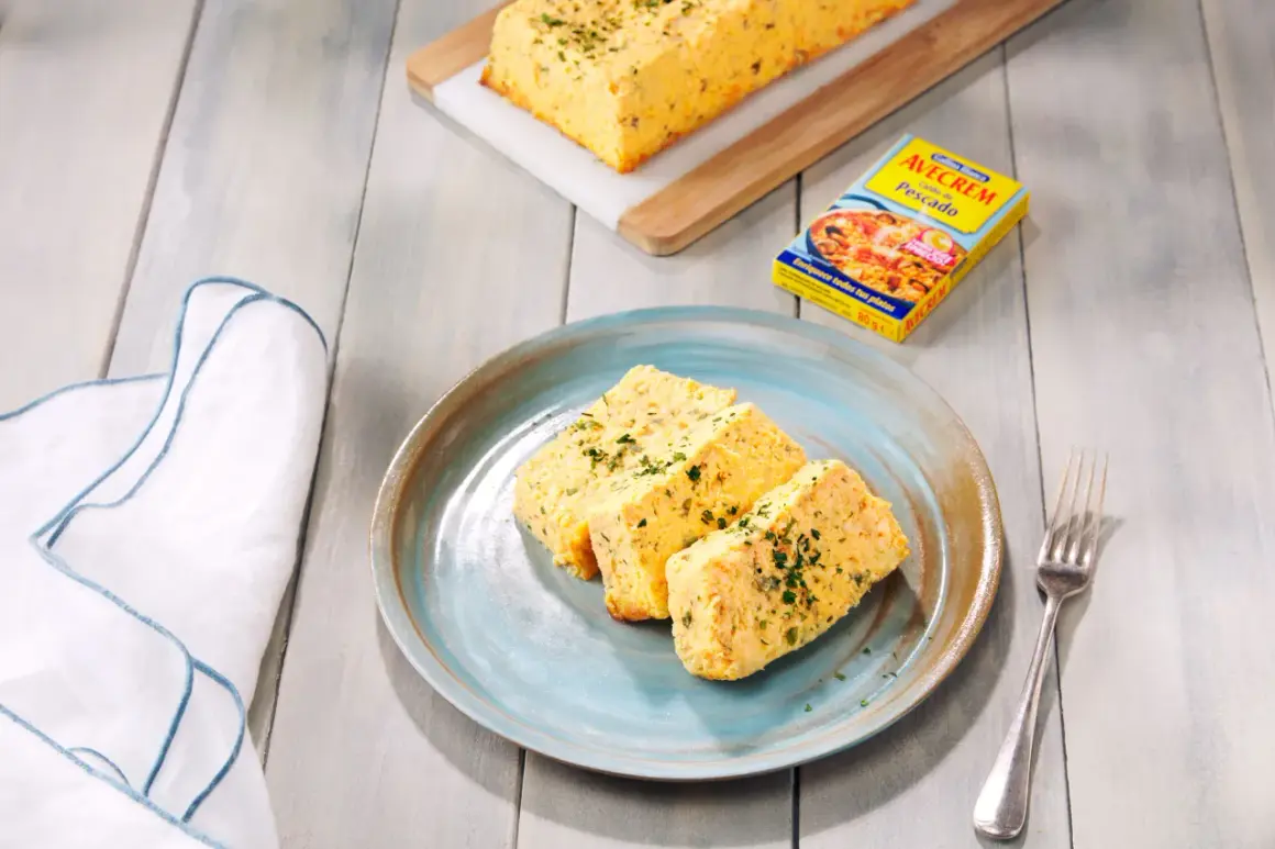 Rebanadas de pastel de pescado, esponjoso y dorado, servido en plato azul. Acompañado de un caldo de pescado.