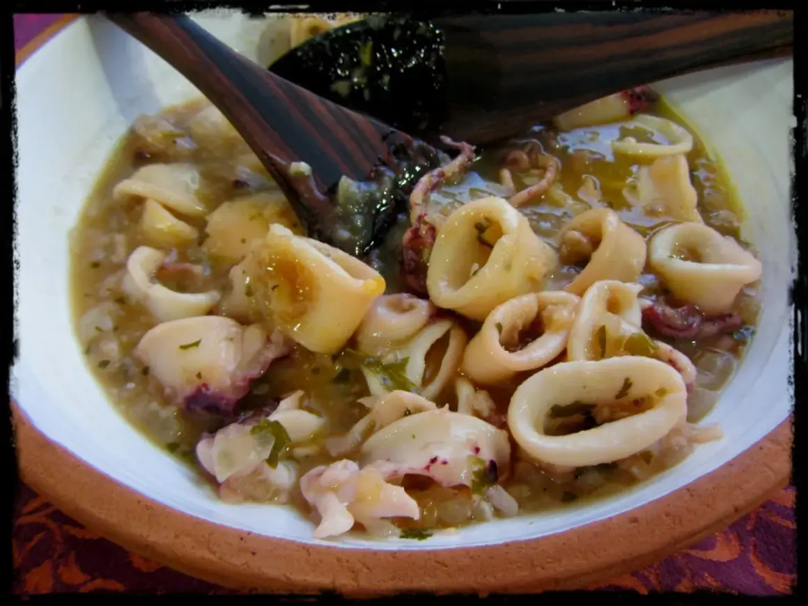 Calamares en salsa, un plato casero con trozos tiernos y tentáculos, servido en un cuenco de barro.