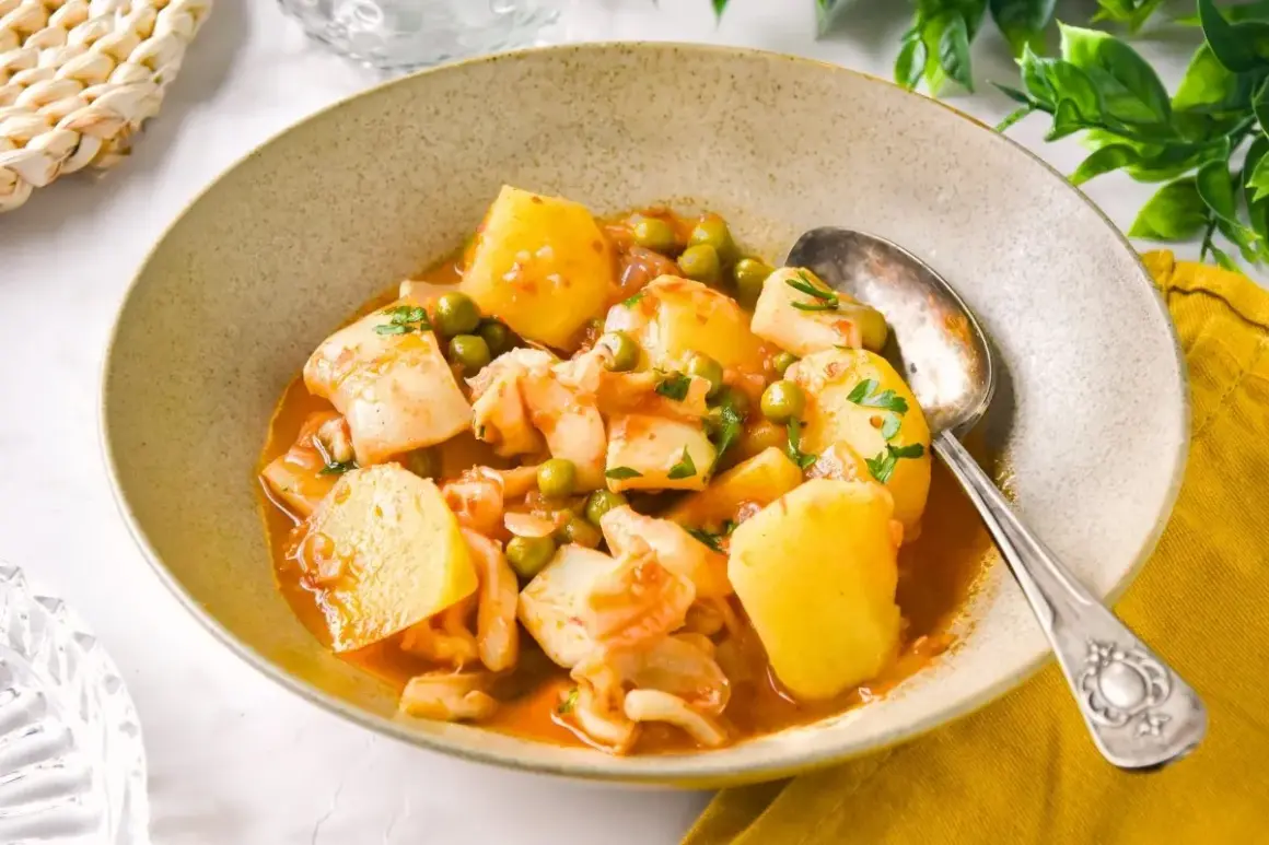 Un plato humeante de patatas con sepia de la abuela, con guisantes y perejil fresco.