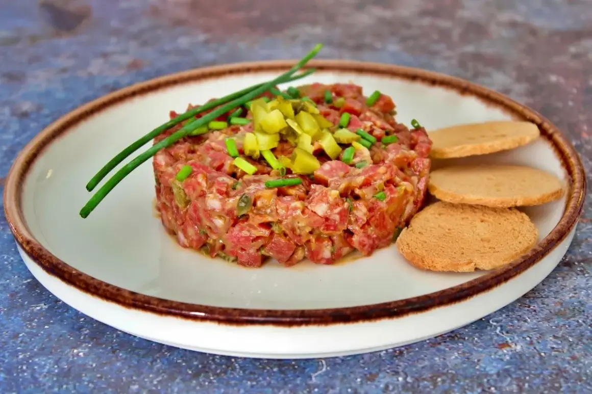 Tartar de salchichón picado finamente, adornado con cebollino y pepinillos, servido con tostas.