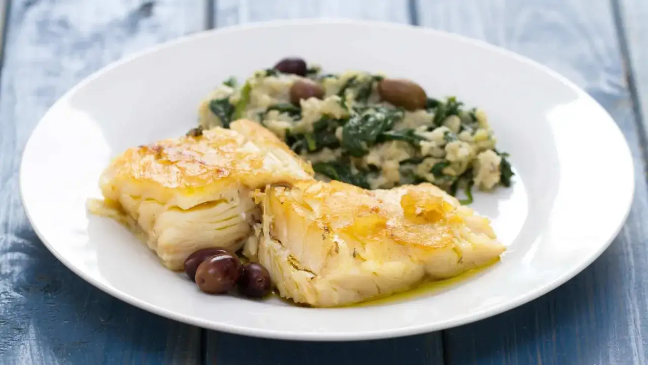 Dos filetes de bacalao en airfryer, dorados y jugosos, acompañados de puré de espinacas y aceitunas negras.
