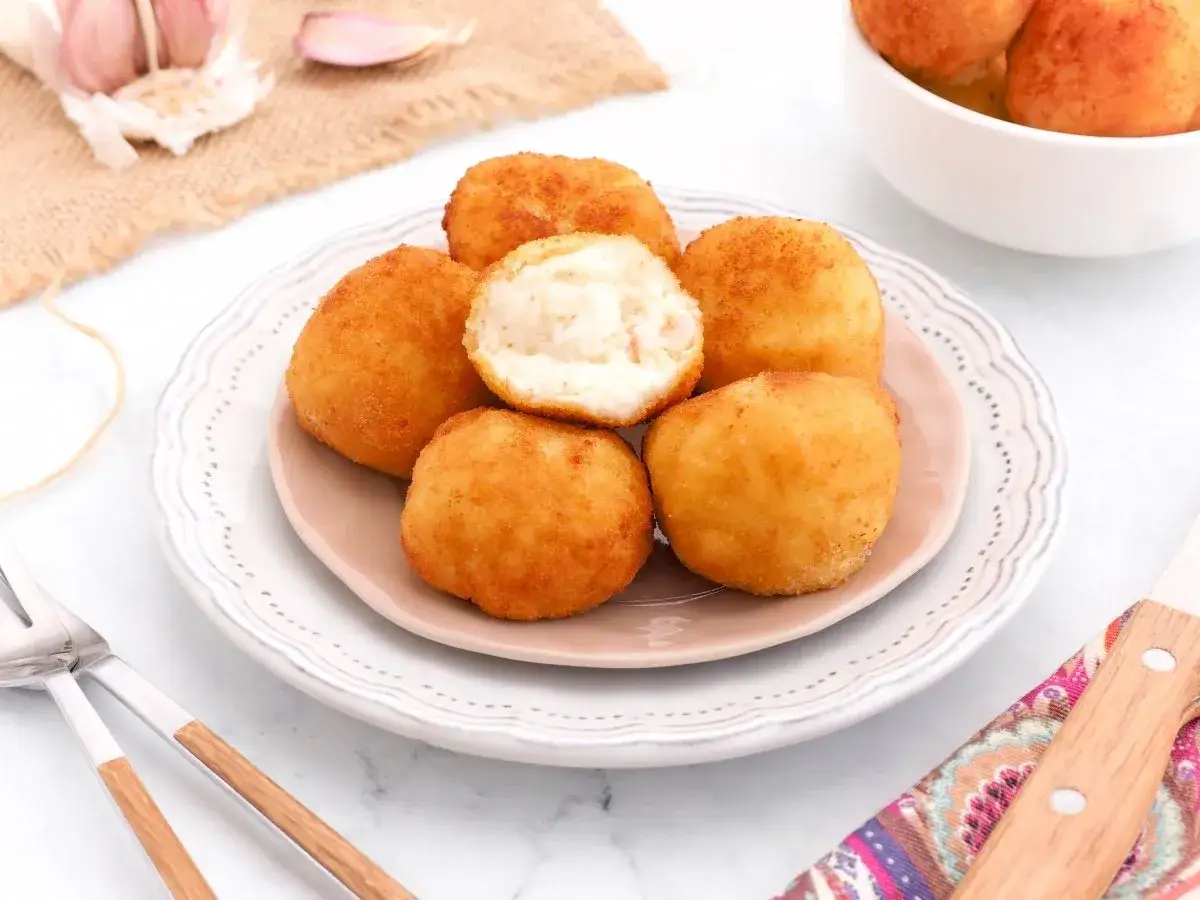 Deliciosas croquetas de gambas doradas y crujientes, una de ellas partida revela su cremoso interior. Perfectas para tapear.
