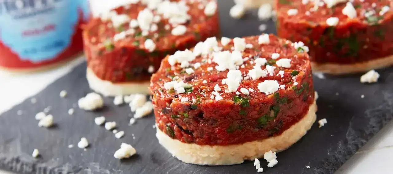 Delicioso tartar de tomate con queso feta desmoronado, servido sobre una base crujiente.