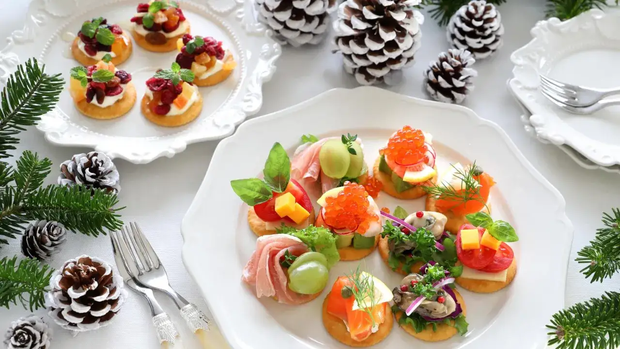 Aperitivos baratos para mucha gente: galletas con salm&oacute;n, caviar, ostras, jam&oacute;n y frutas. Decoraci&oacute;n navide&ntilde;a con pi&ntilde;as y ramas de abeto.