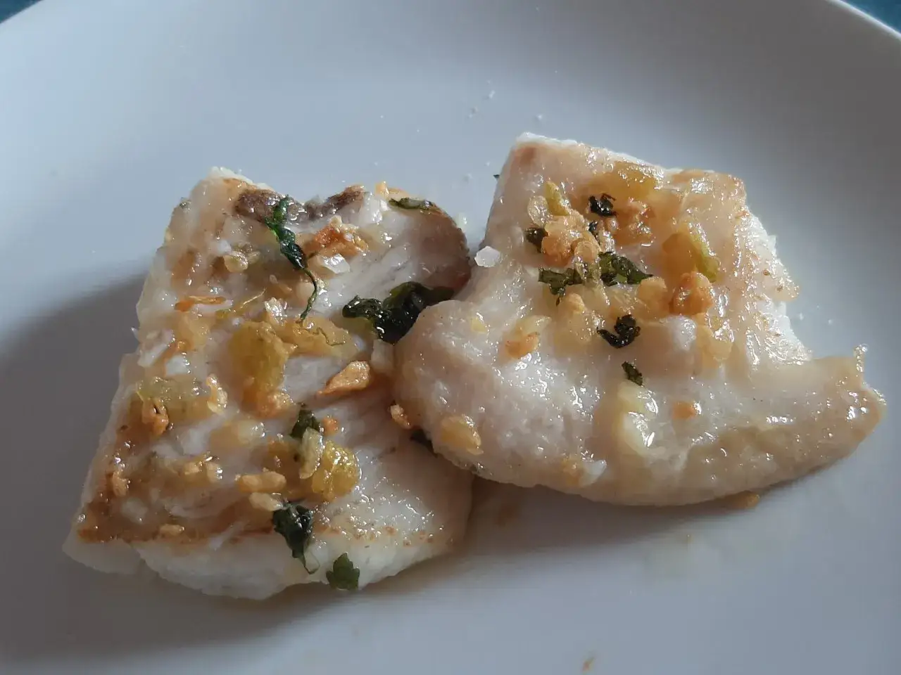 Dos filetes de gallo a la plancha, jugosos y dorados, con ajo y perejil picado.