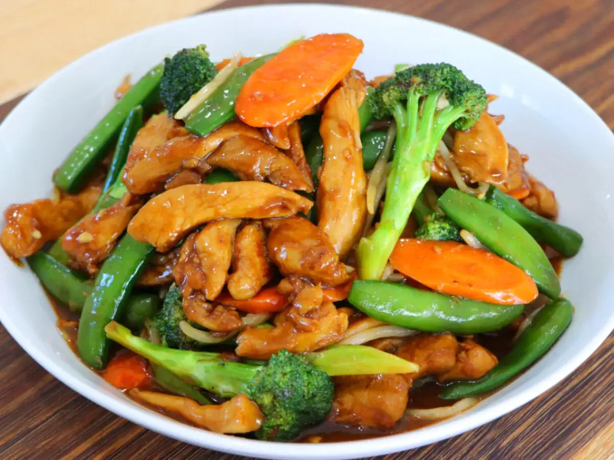 Un delicioso chop suey de pollo con brócoli, zanahoria y guisantes en una salsa sabrosa.