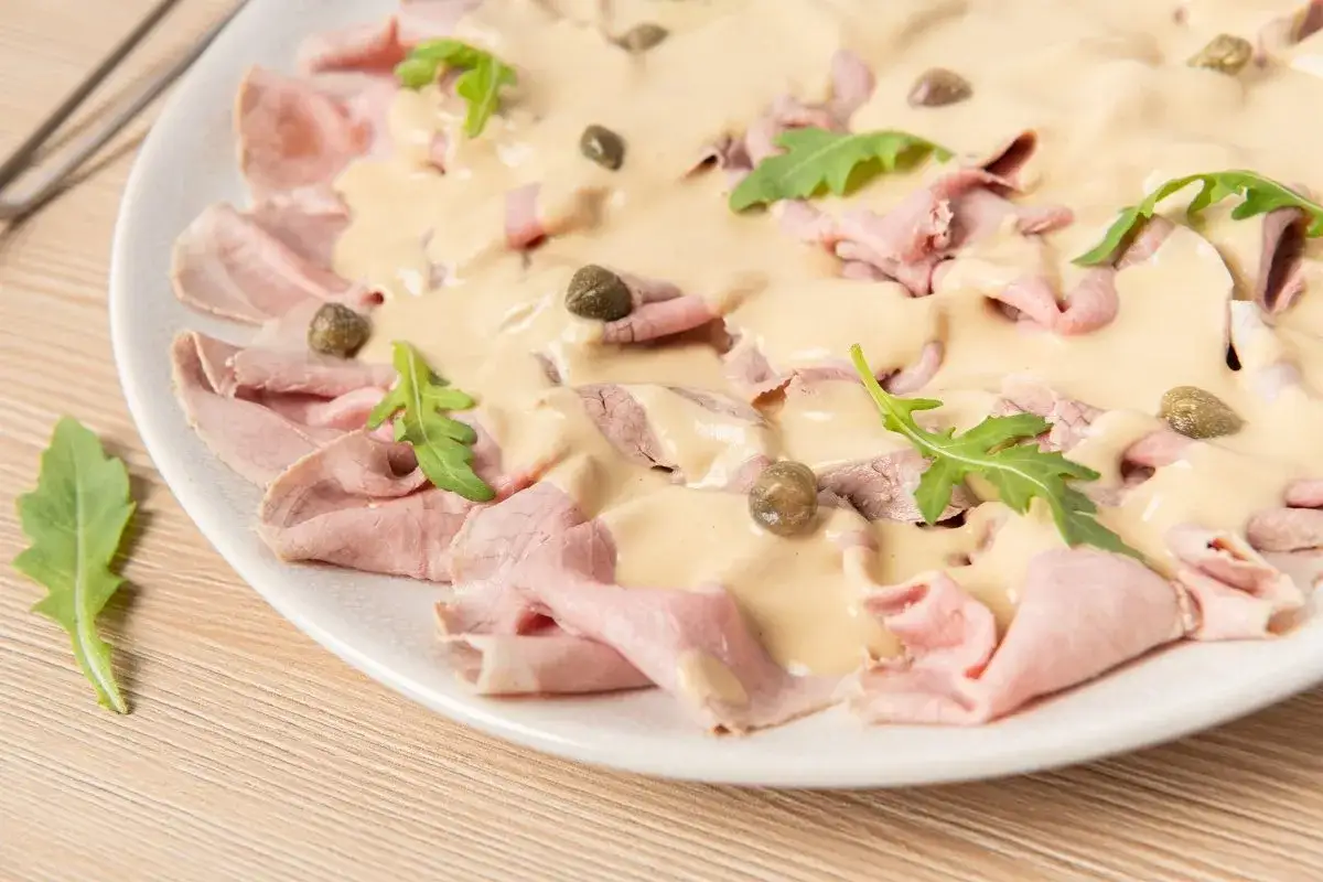 Vitello tonnato con salsa cremosa, alcaparras y r&uacute;cula. Un plato cl&aacute;sico italiano.