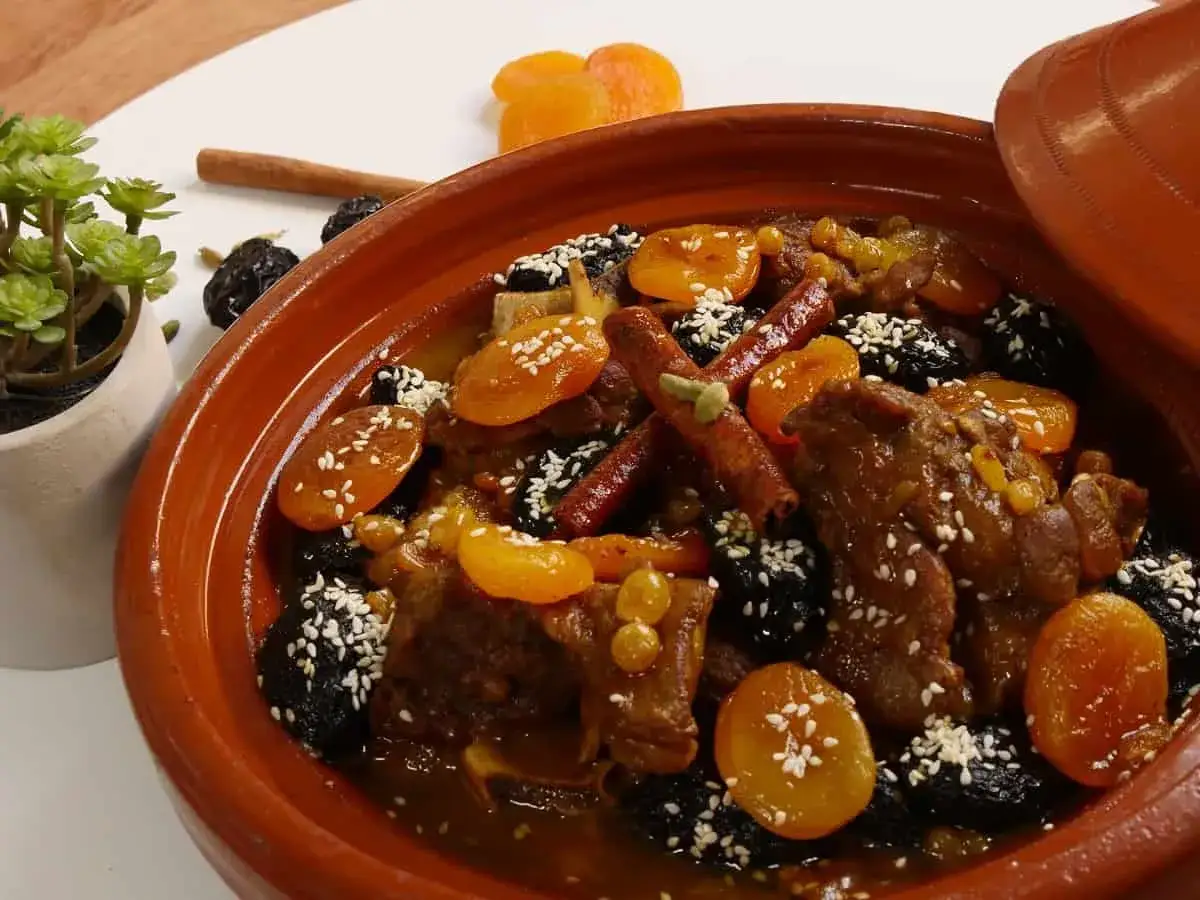 Tajine de cordero con ciruelas pasas, albaricoques secos y semillas de s&eacute;samo, decorado con canela.