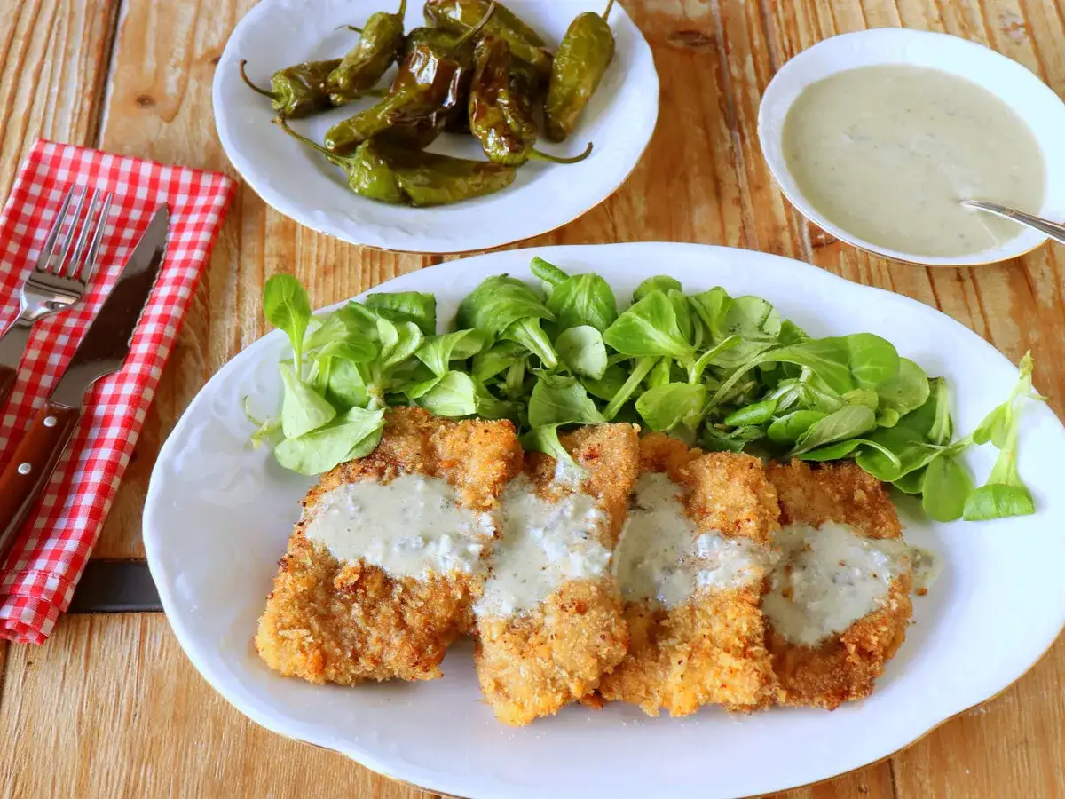 Escalopes empanados con salsa cremosa de cabrales, acompa&ntilde;ados de ensalada verde y pimientos asados.