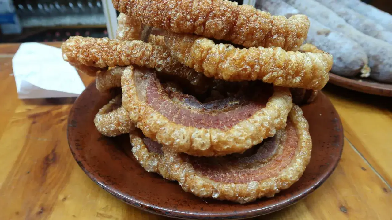 Crujientes torreznos en freidora de aire, apilados en un plato de barro. Perfectos para picar.