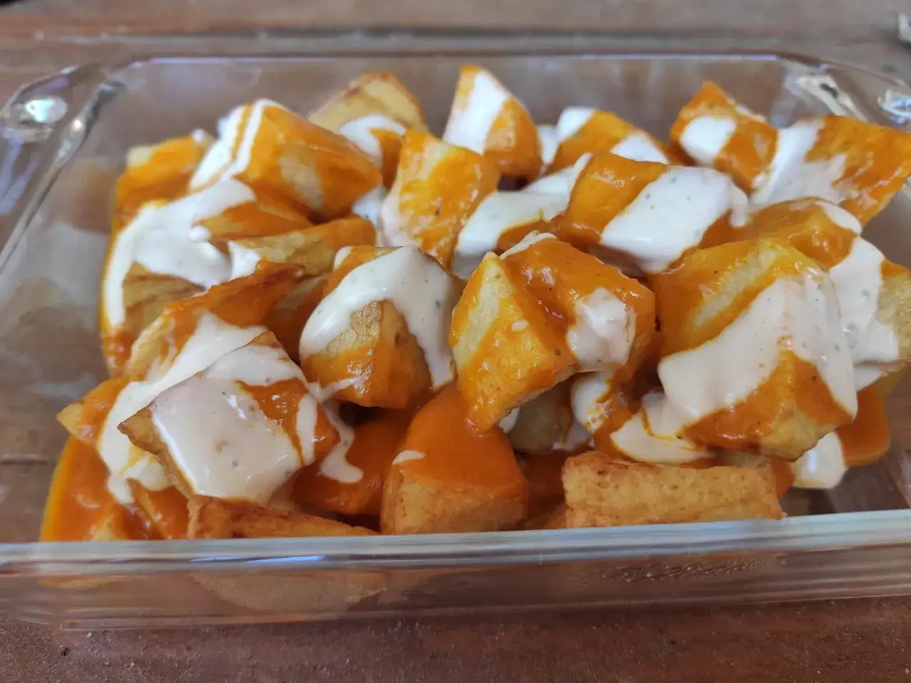 Patatas bravas crujientes ba&ntilde;adas en salsa brava y alioli, un cl&aacute;sico espa&ntilde;ol irresistible.